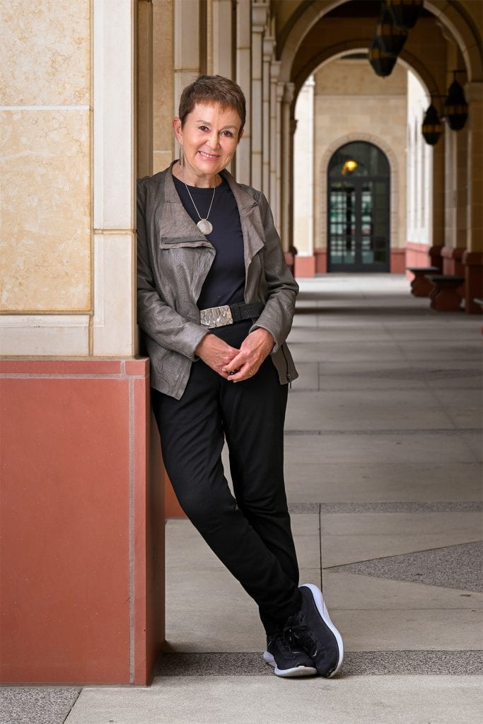 Elizabeth M. Daley leans against an archway in the School of Cinematic Arts building
